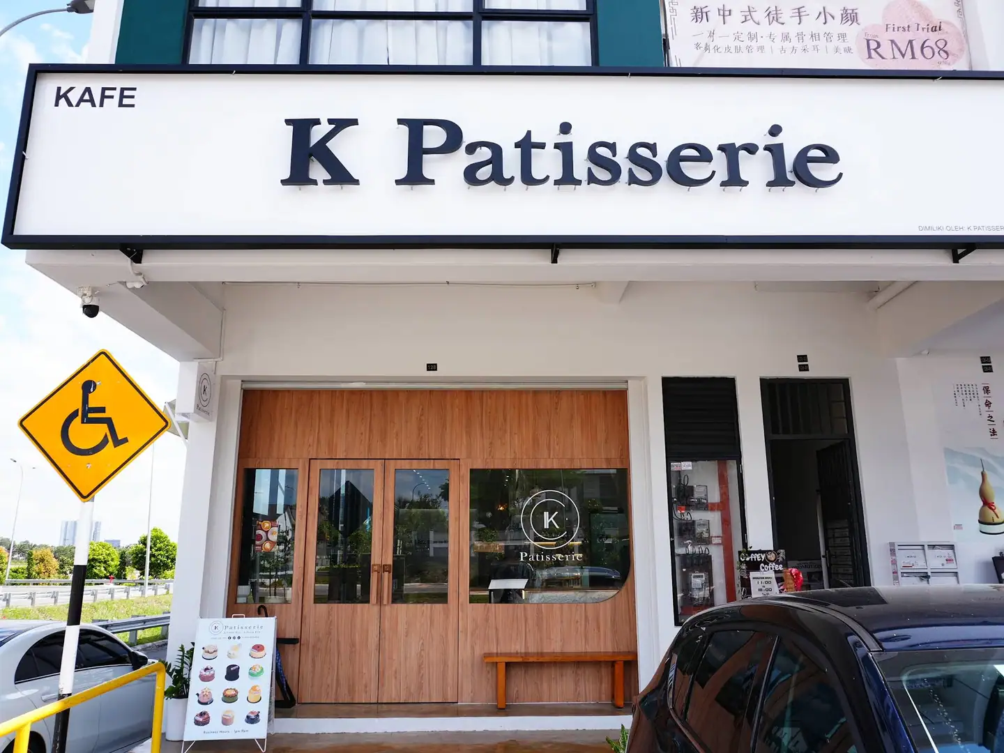 K Patisserie Johor Bahru（Austin Crest）门头：白底黑立体字招牌、橡木门与玻璃。